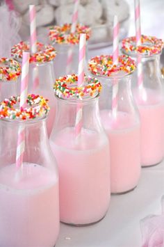 pink milk with sprinkles and straws in small glass bottles on a table