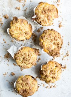 four muffins sitting on top of a white paper covered in crumbs