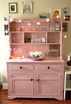 a pink china cabinet with wine glasses on top