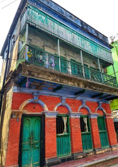 an old red brick building with green doors and balconies on the second floor