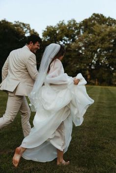 a bride and groom walking through the grass