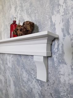 a white shelf with two bottles on top of it next to a wall paper roll