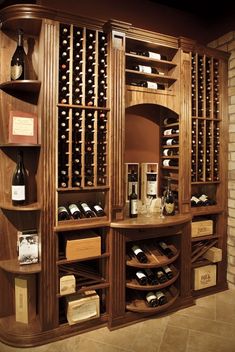 a wine cellar filled with lots of bottles and glasses on top of wooden shelves next to a brick wall