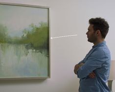 a man standing in front of a painting with his arms crossed and looking at it