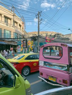 a pink bus driving down a busy street next to other cars and people on the sidewalk