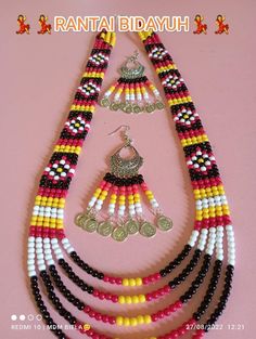 a necklace and earring set made from beads with coins on it, sitting on a pink surface