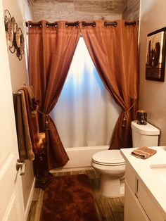 a bathroom with a toilet, sink and bathtub covered in brown curtained drapes