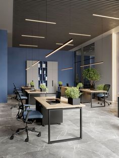 an empty office with desks and plants on the tables in front of them,