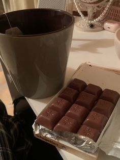 a box of chocolate next to a cup on a table