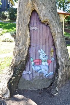 a tree trunk with a painted door in it's bark and some leaves on the ground