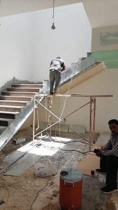 two men are working on an unfinished staircase