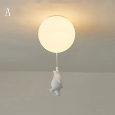 a white lamp hanging from the ceiling with a bear on it's back end