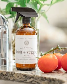 a bottle of fruit and veggie wash next to three tomatoes on a counter