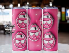 three pink tumblers with faces painted on them sitting on a table in a restaurant