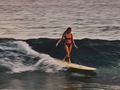 a woman riding a surfboard on top of a wave in the middle of the ocean