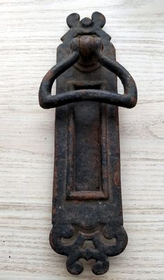 an old iron door handle on a white wooden surface with no one in the photo