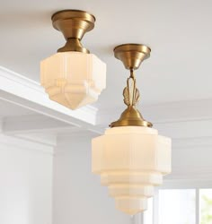 two light fixtures hanging from the ceiling in a room with white walls and flooring