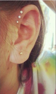 a woman's ear with three piercings on it