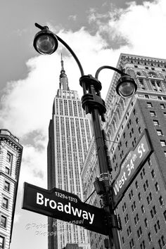 black and white photograph of broadway street sign in new york city with skyscrapers in the background