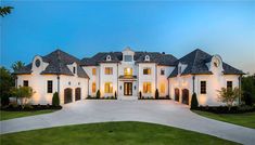 a large white house with lots of windows on the front and side of it at night