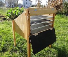 a wooden stand with an open shelf on it in the middle of some green grass