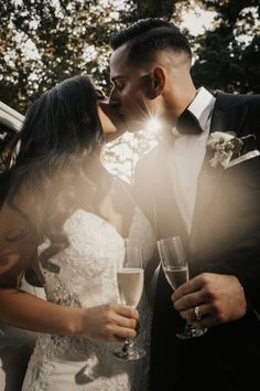 a bride and groom kissing while holding champagne flutes