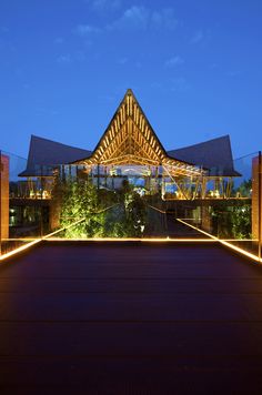 the entrance to a building lit up at night with lights on it and trees in front