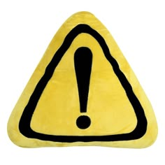 a yellow triangle shaped pillow with a black exclamation sign on the front