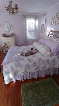 a dog laying on top of a bed in a room with wooden floors and pink walls