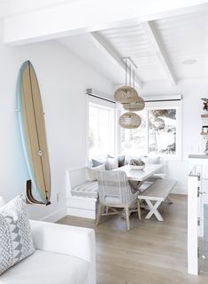 a living room with a surfboard hanging from the ceiling next to a dining table