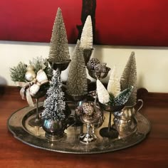 a tray topped with silver cups filled with christmas trees