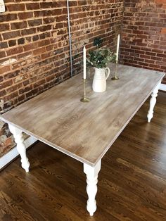 a wooden table with candles on it in front of a brick wall and wood floor