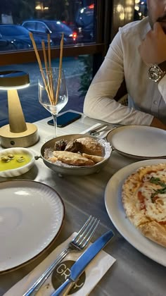 a man sitting at a table in front of plates with pizza on them and silverware