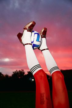 two legs in red and white socks holding a soccer ball