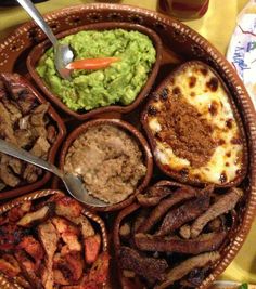 a platter filled with meat, guacamole and other condiments