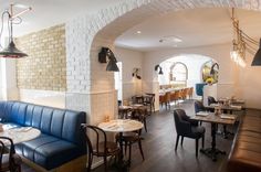 an empty restaurant with blue booths and white brick walls, along with wooden tables and chairs