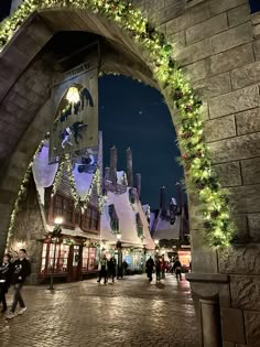 people walking under an archway decorated with christmas lights