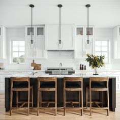 a kitchen with white cabinets and wooden stools in front of an island countertop