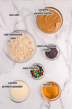 ingredients to make peanut butter in bowls on a white marble counter top with text overlay