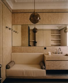 a white couch sitting under a mirror next to a sink