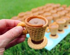 a person is holding up a cookie in front of some cups