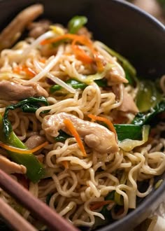 a bowl filled with noodles, meat and veggies next to chopsticks