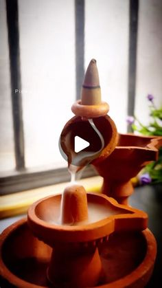 a clay fountain with a candle in it on a table next to a flower pot