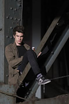 a man sitting on top of a metal structure with his feet up in the air