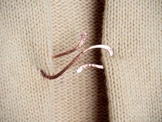 a pair of pink scissors sticking out of the side of a sweater