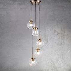 a chandelier with five glass globes hanging from it's brass finish