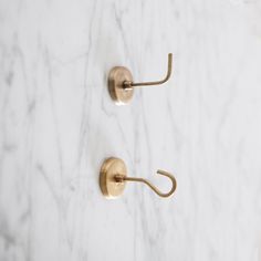 two brass hooks on a white marble wall