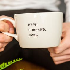 a person holding a coffee mug with the words best husband ever