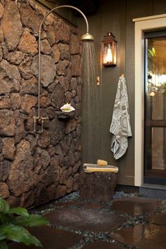 a bathroom with stone walls and an open shower head next to a door that has a towel hanging on it