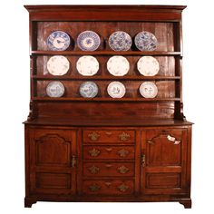 an old wooden china cabinet with plates on it